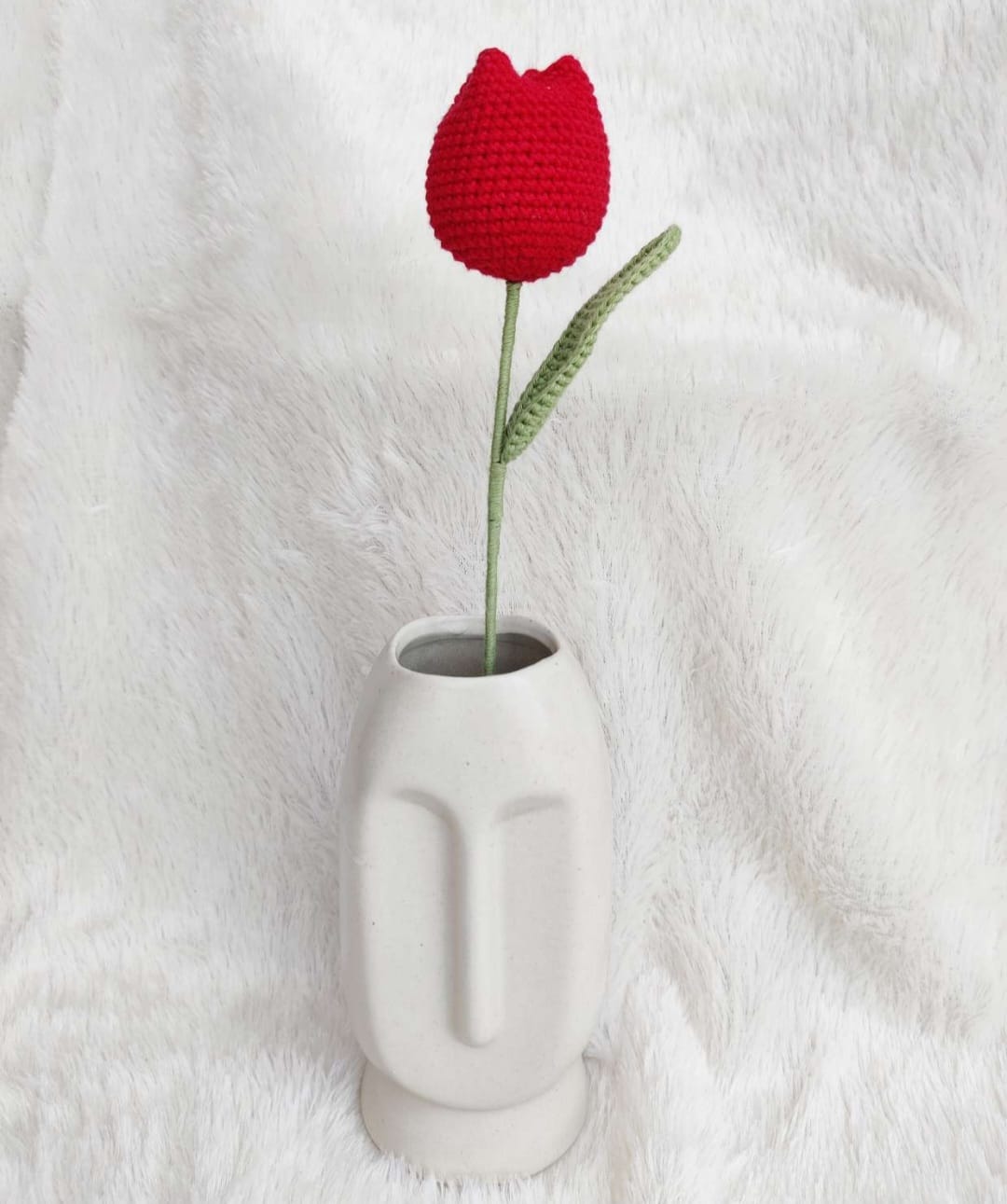White vase with a red crocheted tulip on a white background