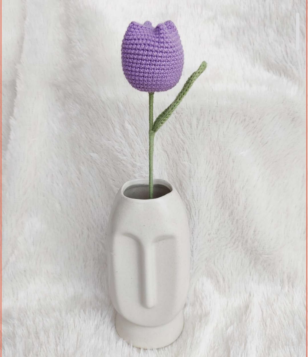 Crocheted purple tulip in a white vase on a white background