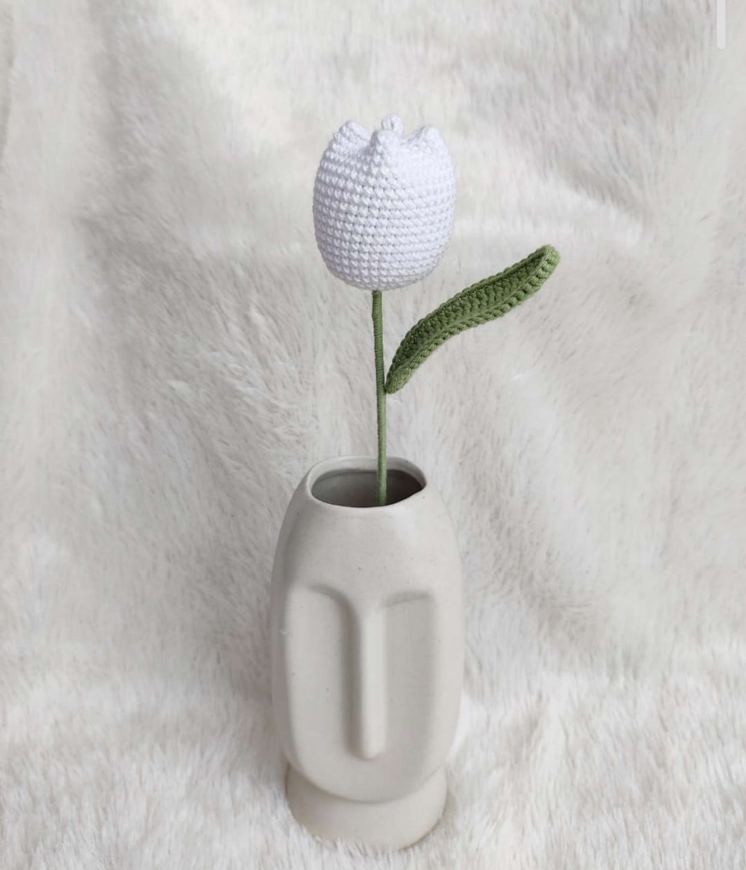 Crocheted tulip in a small white vase on a white background